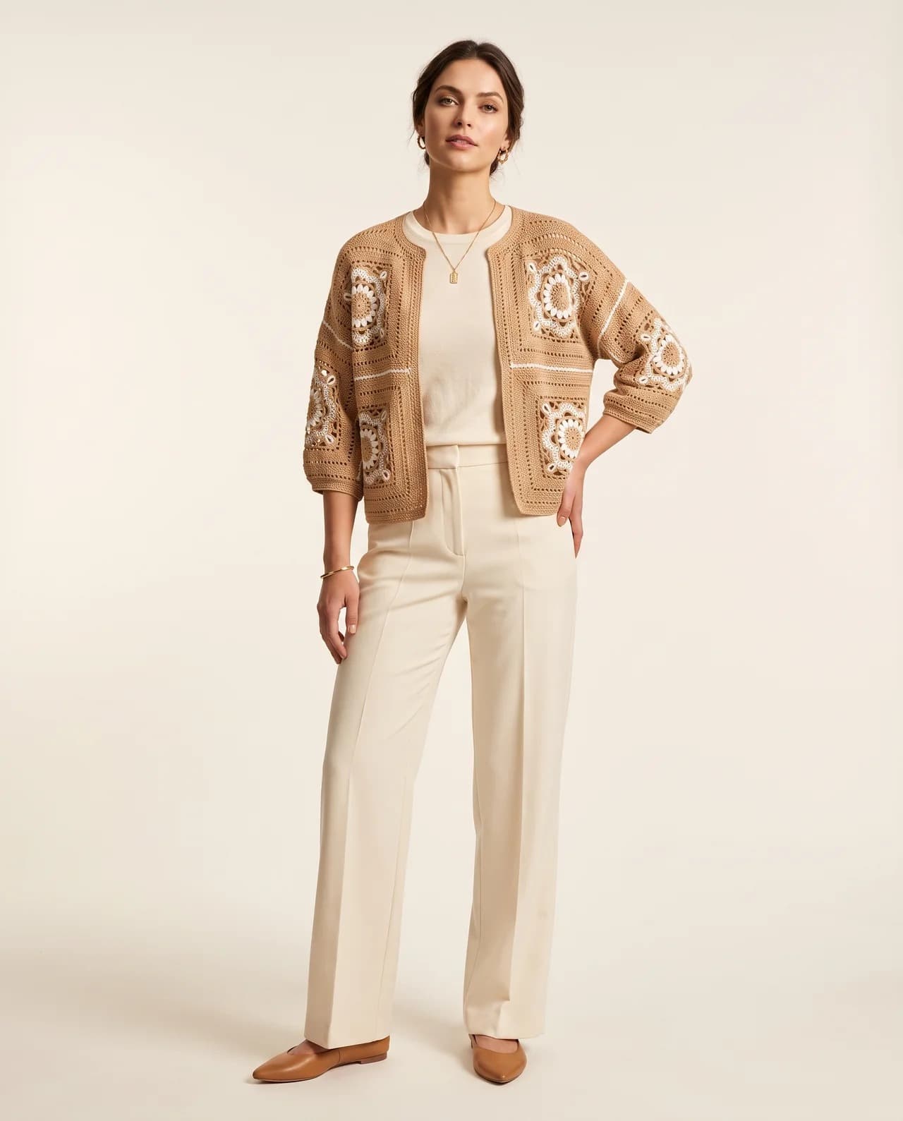 Krem çiçek motifli camel rengi kare motifli tığ işi hırkayı krem pantolon üzerine giyen manken